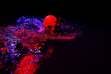 Image showing real triathlon athlete swimming in dark night