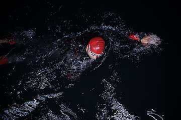 Image showing triathlon athlete swimming in dark night wearing wetsuit