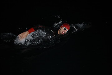 Image showing triathlon athlete swimming in dark night wearing wetsuit