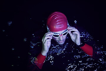 Image showing authentic triathlete swimmer having a break during hard training on night