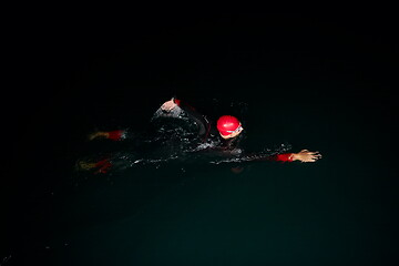 Image showing triathlon athlete swimming in dark night wearing wetsuit