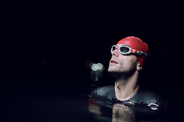 Image showing authentic triathlete swimmer having a break during hard training on night