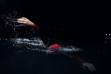 Image showing triathlon athlete swimming in dark night wearing wetsuit