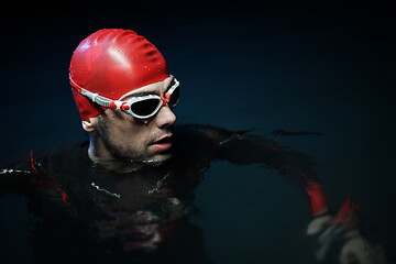 Image showing authentic triathlete swimmer having a break during hard training on night