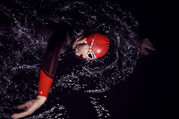 Image showing triathlon athlete swimming in dark night wearing wetsuit