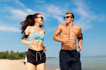 Image showing couple with phones and arm bands running on beach