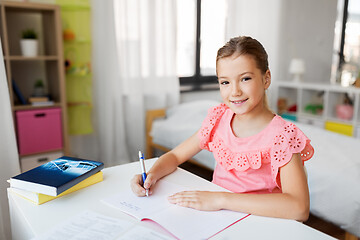 Image showing student girl with book writing to notebook at home