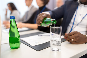 Image showing businessman pouring water to glass at conference