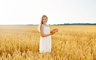 Image showing girl with loaf of white bread on cereal field