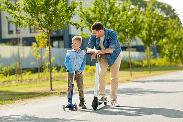 Image showing father and little son riding scooters in city