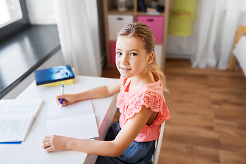 Image showing student girl with book writing to notebook at home