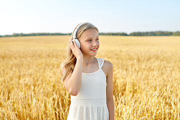 Image showing happy girl in headphones on cereal field in summer