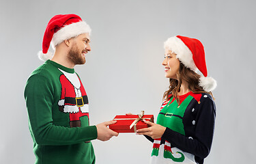 Image showing happy couple in christmas sweaters with gift box