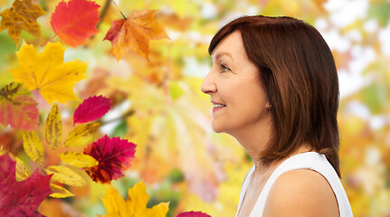 Image showing profile of smiling senior woman over autumn leaves