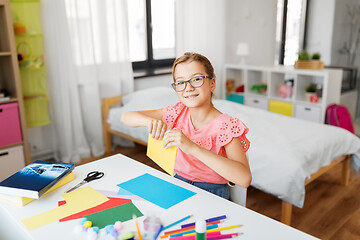 Image showing girl with color paper sitting at table at home