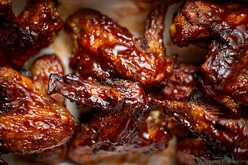 Image showing Close up on Chicken wings in thick barbecue sauce. Served on white cast iron dish