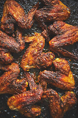 Image showing Grilled chicken wings in spices in black metal baking tray on stone table. Top view