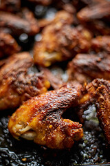 Image showing Grilled chicken wings in spices in black metal baking tray on stone table. Top view