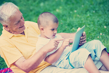 Image showing grandfather and child in park using tablet