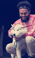 Image showing young man playing with dog in front of wooden house