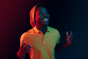 Image showing Portrait of a happy young african american man smiling on black neon background