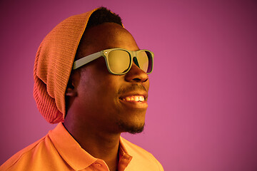 Image showing Portrait of a happy young african american man smiling on black neon background
