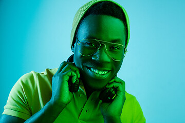 Image showing Portrait of a happy young african american man smiling on black neon background