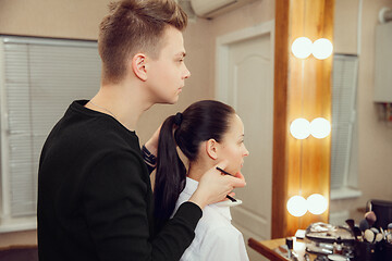 Image showing Professional makeup artist working with beautiful young woman