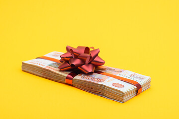 Image showing On a yellow background lies a gift pack of five thousandth Russian bills