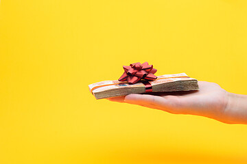 Image showing Hand gives a pack of five thousandth bills on a yellow background