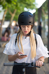 Image showing Woman using smartphone and renting modern electric scooter with an application. Urban transport concept