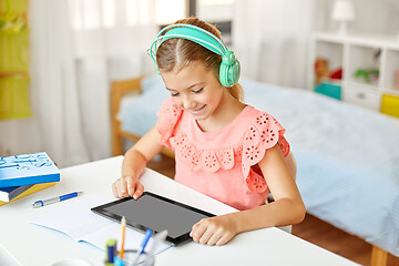 Image showing girl in headphones with tablet computer at home