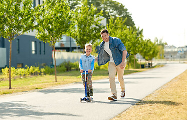 Image showing happy father and little son riding scooter in city