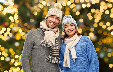 Image showing happy couple in winter hats over christmas lights