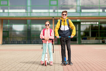 Image showing happy school children with backpacks and scooters