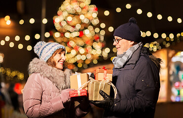 Image showing happy senior couple with gift at christmas market