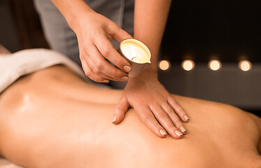 Image showing back massage with hot oil candle at spa