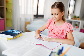 Image showing student girl with book writing to notebook at home