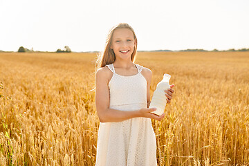 Image showing happy girl with bottle of milk on cereal field