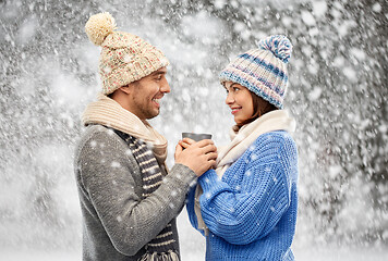 Image showing happy couple in winter clothes holding one cup