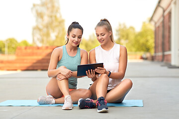 Image showing sporty women or friends with tablet pc on rooftop