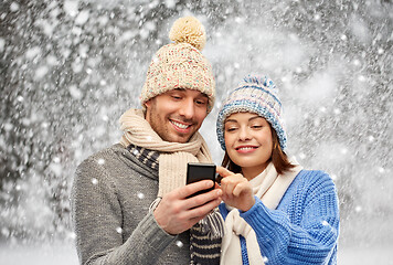 Image showing happy couple in winter clothes with smartphone