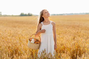 Image showing girl with bread and milk in basket on cereal field