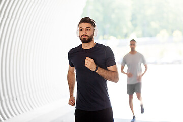 Image showing male friends with headphones running outdoors