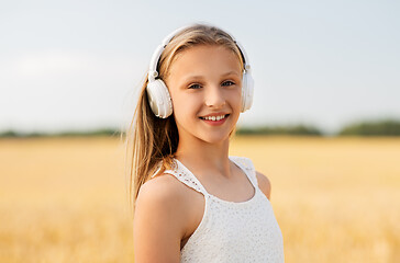 Image showing happy girl in headphones on cereal field in summer