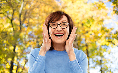 Image showing senior woman in glasses calling over autumn park