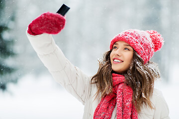 Image showing young woman taking selfie by smartphone in winter