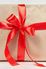 Image showing Big red bow from silk ribbon on a gift box. Close-up view.