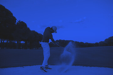 Image showing golfer hitting a sand bunker shot on sunset