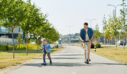 Image showing father and little son riding scooters in city